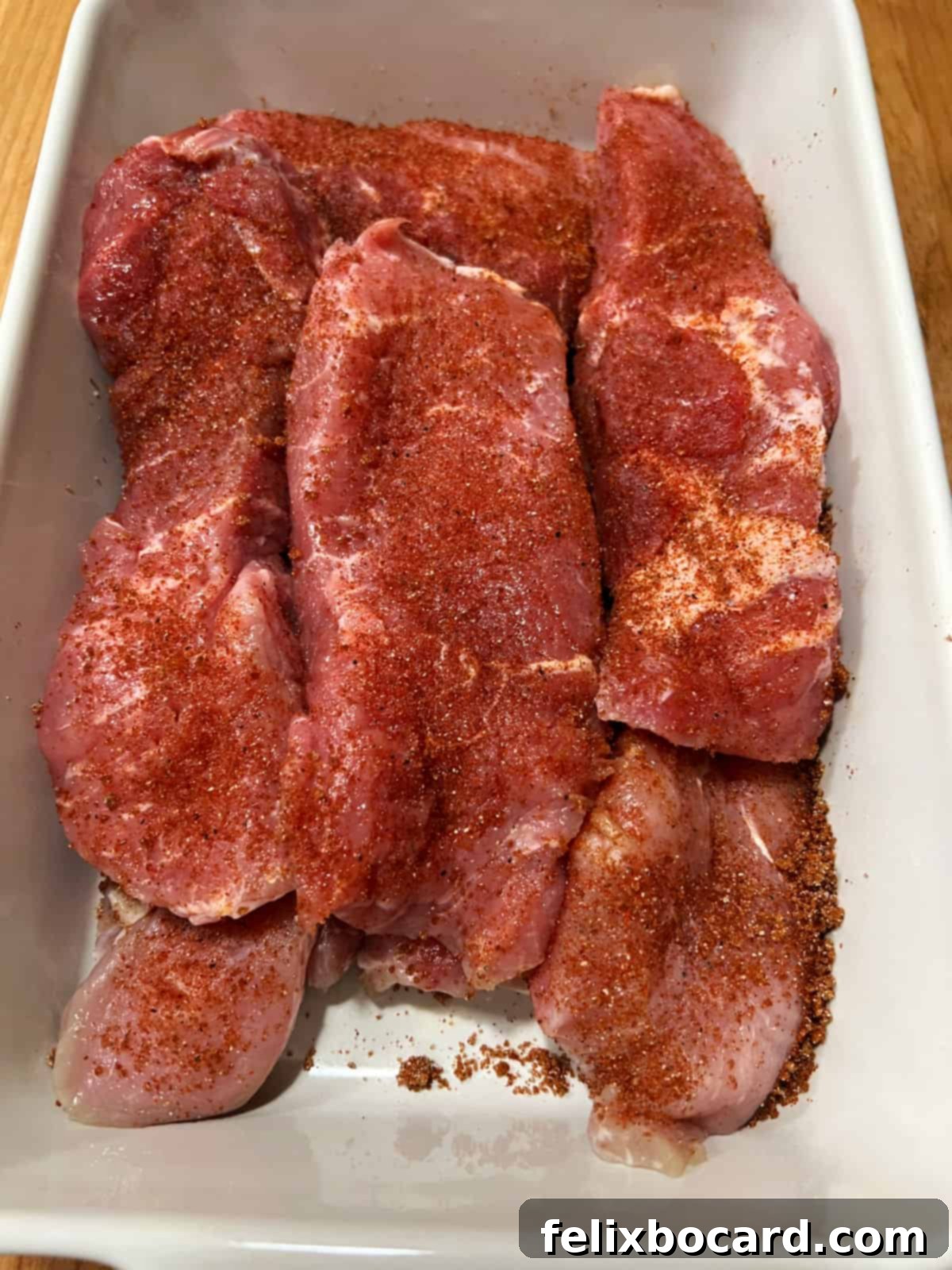 A pan filled with pork strips generously coated in a sweet dry rub, marinating before cooking.