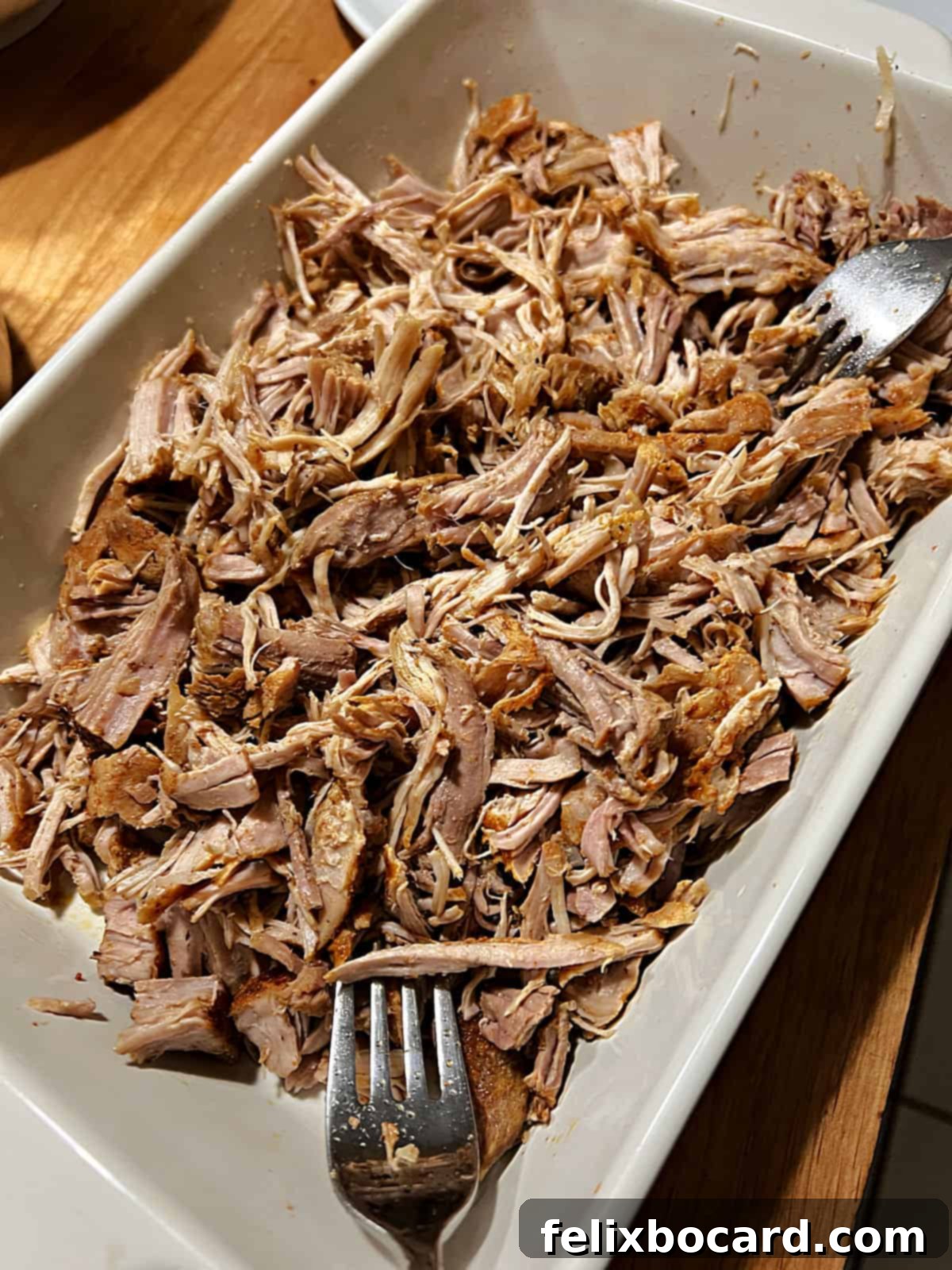 Two forks actively shredding tender pulled pork, removed from the Instant Pot, ready for serving.