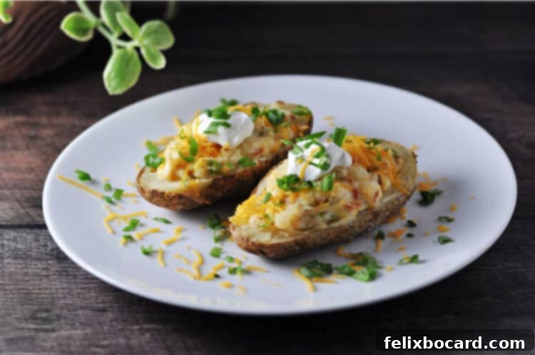 Two halves of grilled twice baked potatoes on a plate, garnished with green onions