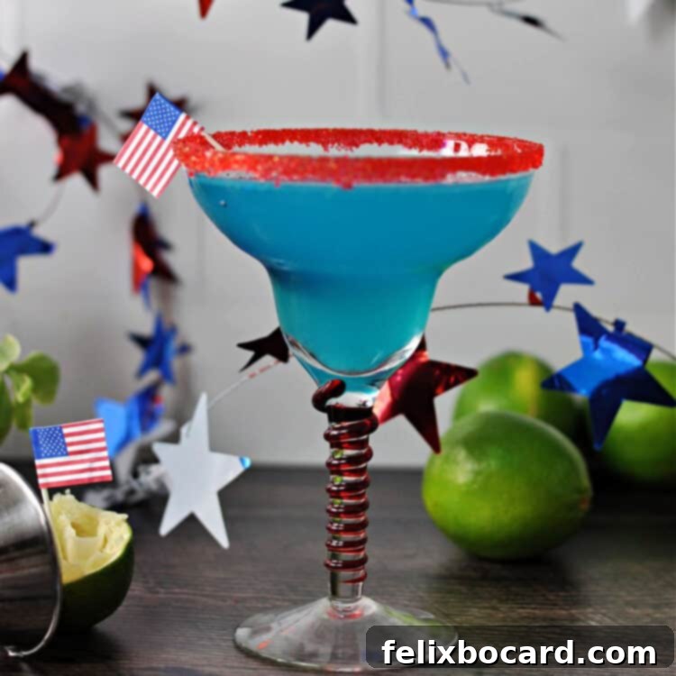Blue margarita in a red rimmed glass, surrounded by garland stars and some limes