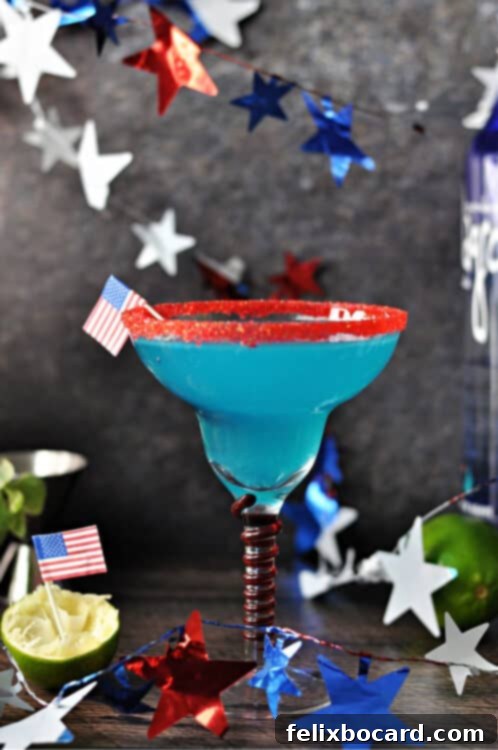 Firecracker blue margarita in a red rimmed glass, surrounded by a garland of stars