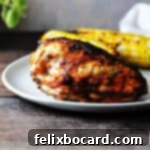 keto BBQ chicken breast on a plate with 2 ears of cooked corn on the same plate