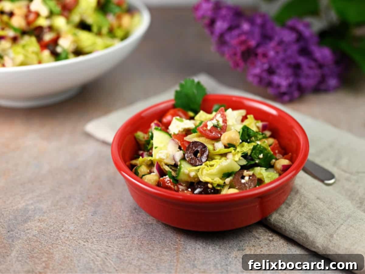 A vibrant serving of Mediterranean chopped salad in a small red bowl, showcasing the fresh, colorful ingredients.