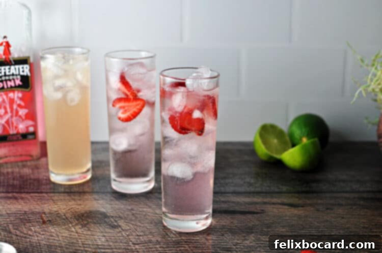 Three tall, slender glasses holding subtly pink-tinted gin and tonic cocktails, garnished with citrus.