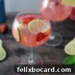 Blush Gin Sparkler 6 Pink gin and lemonade in a wine glass garnished with slices of lemon, lime and strawberries