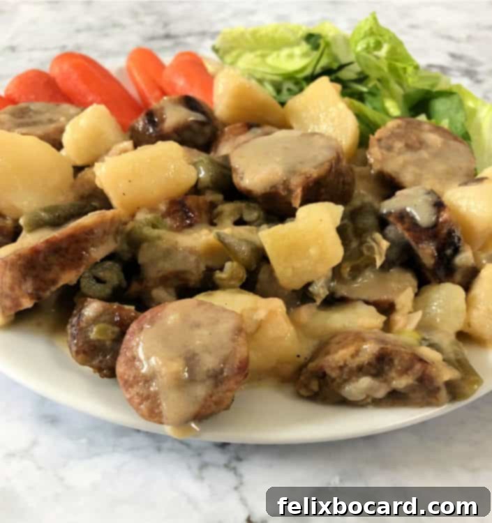 A close-up shot of the Cheesy Bratwurst Casserole served on a plate, garnished with some fresh herbs, alongside a small portion of roasted carrots and a green salad. The casserole looks rich and inviting.