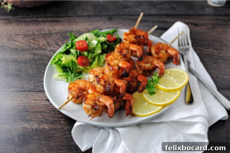 Cajun shrimp kabobs on a plate with a small green salad and lemon slices