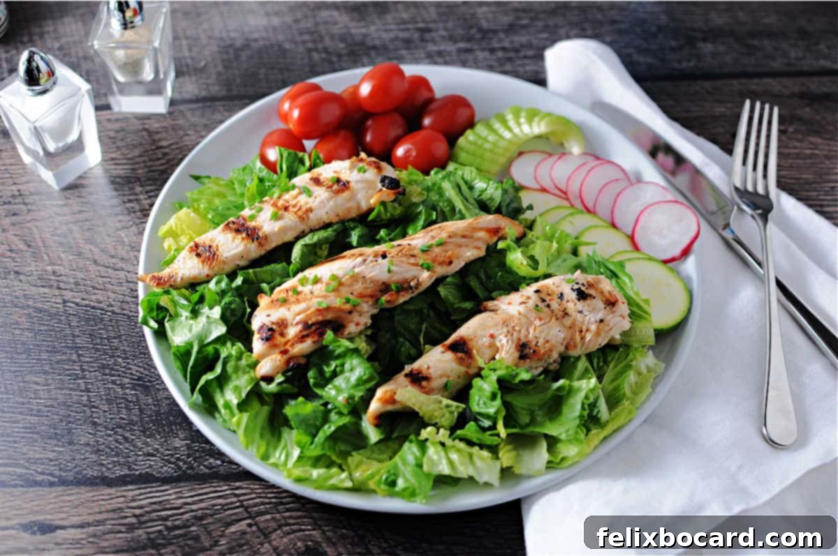 Chargrilled Chicken Strips 2 Three perfectly grilled chicken tenders served on a vibrant bed of fresh salad greens, showcasing their golden-brown char marks.