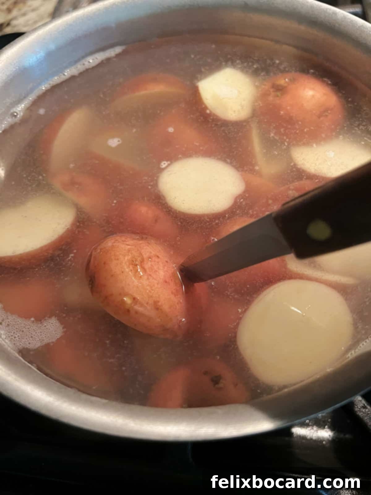 Creamy Red Potato Salad 6 Checking potatoes for doneness with a knife.