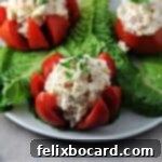 tuna stuffed tomato on a lettuce covered plate with 2 others behind