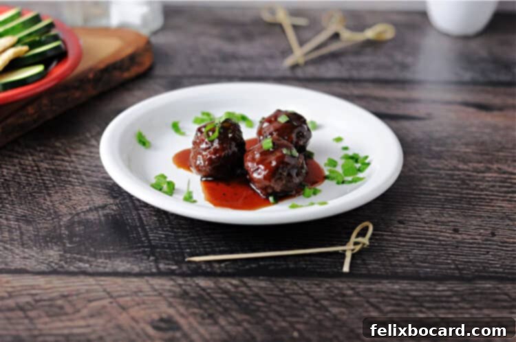 Three succulent grape jelly BBQ meatballs, glistening with a rich, sweet, and tangy sauce, served on a small white plate.