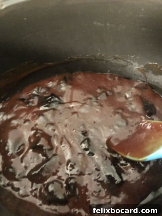 Grape jelly and BBQ sauce being poured into the basin of a slow cooker, ready to be mixed for the meatball sauce.