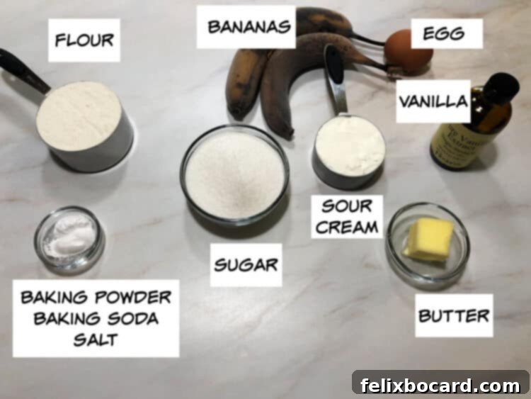 Golden Air Fryer Banana Bread 3 A collection of banana bread ingredients: flour, ripe bananas, egg, vanilla extract, sour cream, sugar, baking powder, baking soda, and salt arranged on a surface.