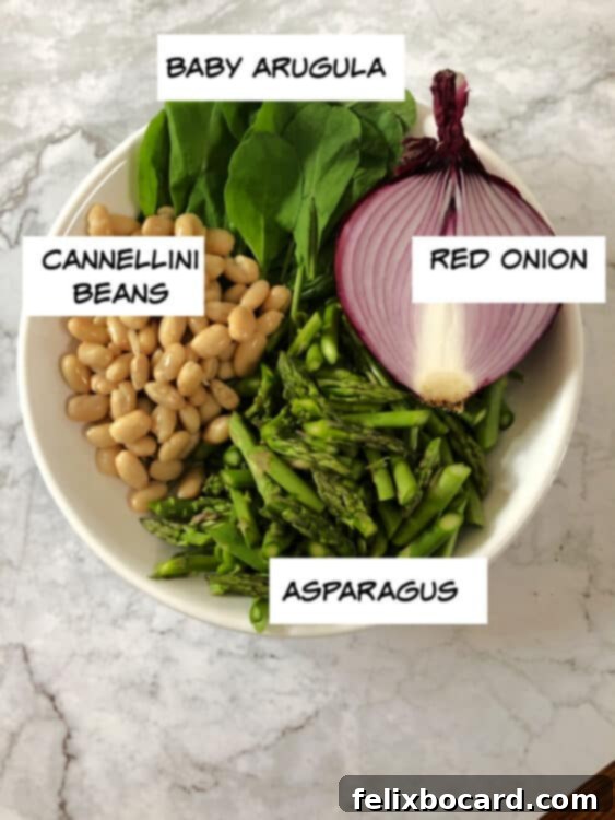 Ingredients for salad: arugula, cannellini beans, sliced red onion, and chopped asparagus