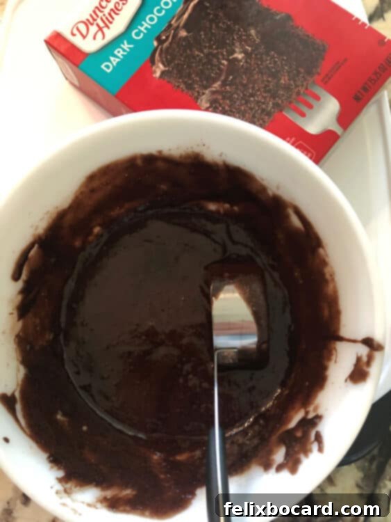 A mixing bowl filled with smooth, chocolate-colored cake mix waffle batter, ready to be poured into the waffle iron.