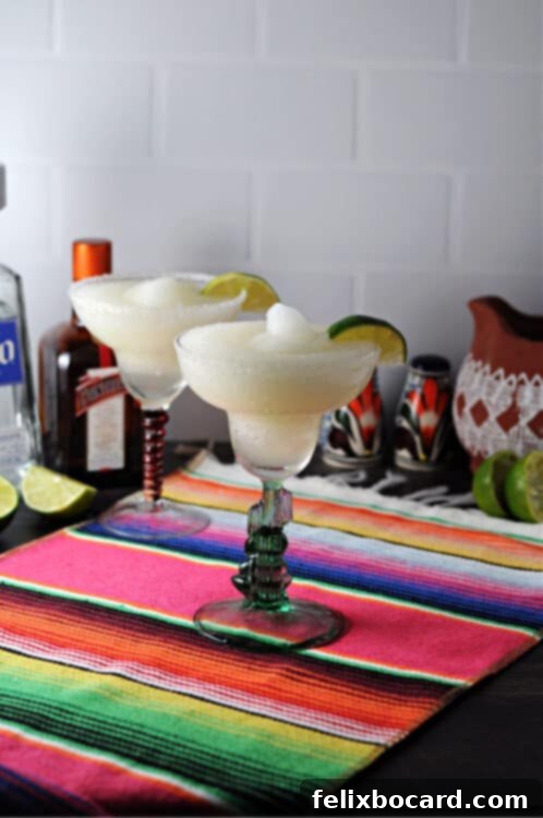 Two perfectly blended frozen margaritas in classic glasses, set on a bright striped table runner, ready to be enjoyed.