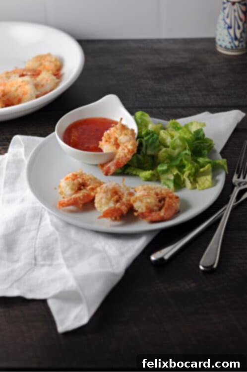 Crispy Air Fryer Coconut Shrimp 2 Crispy Air Fryer Coconut Shrimp served on a small plate with a tangy dipping sauce and a side green salad
