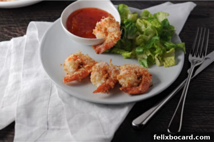 Crispy Air Fryer Coconut Shrimp 5 Air fried coconut shrimp on a small plate with dipping sauce and a refreshing green salad