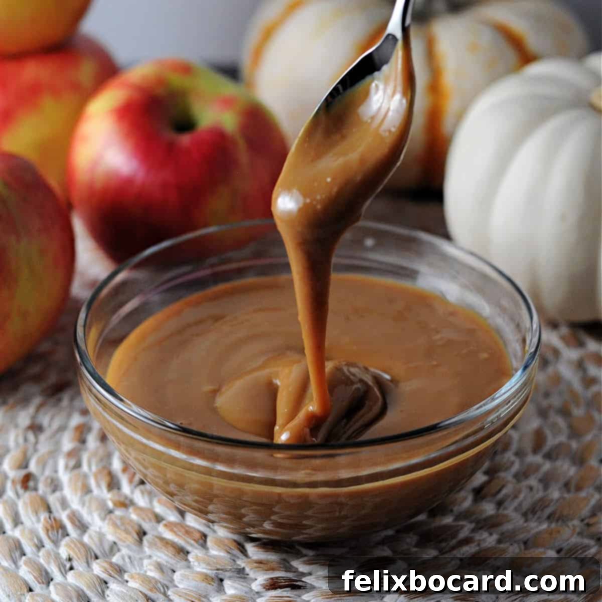 Instant Pot Dulce de Leche 8 Instant pot caramel sauce dripping from a spoon into a bowl, emphasizing its silky smooth texture.