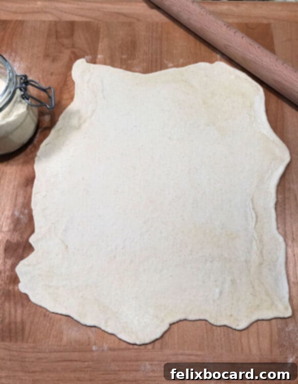 Raw pizza dough rolled out on a cutting board, lightly dusted with semolina flour, ready for grilling.