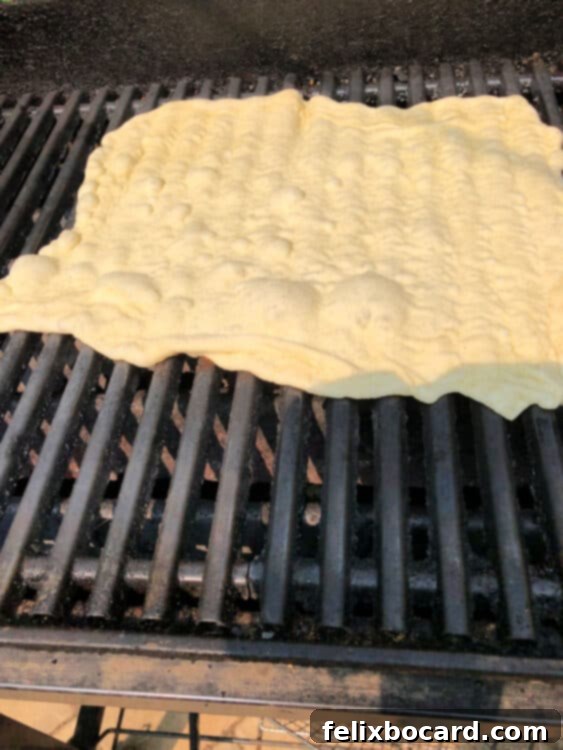 Close-up of bubbles forming in the pizza crust while it cooks on the grill, indicating active cooking.