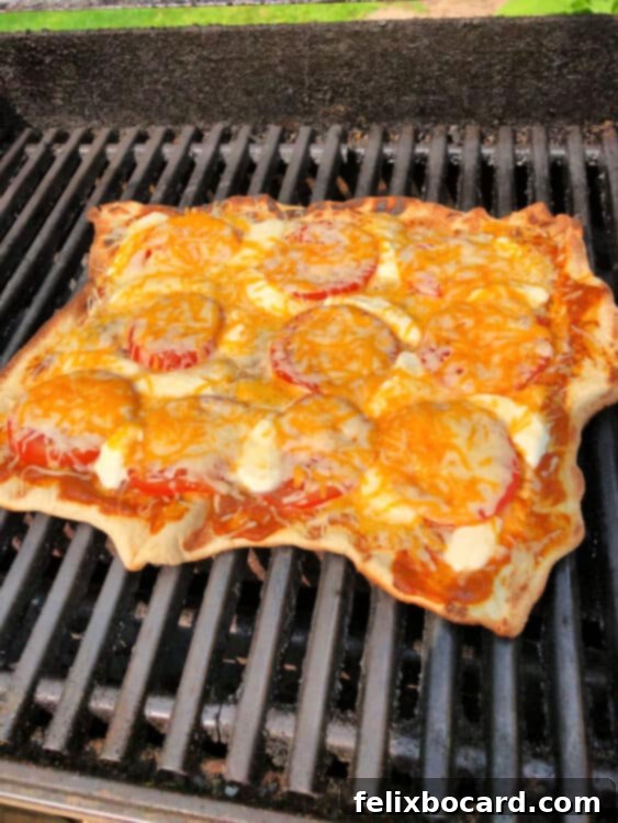 Grilled pizza on the grill, showcasing perfectly melted cheese and thoroughly heated ingredients, indicating readiness for removal.