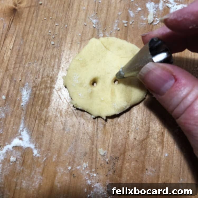 Close-up of cookie dough being cut with a Wilton tip to make small holes for vampire bite marks.