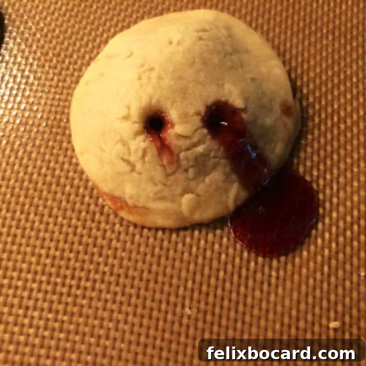 Baked vampire kiss cookies on a cooling rack, with some jam slightly oozing from the bite marks.