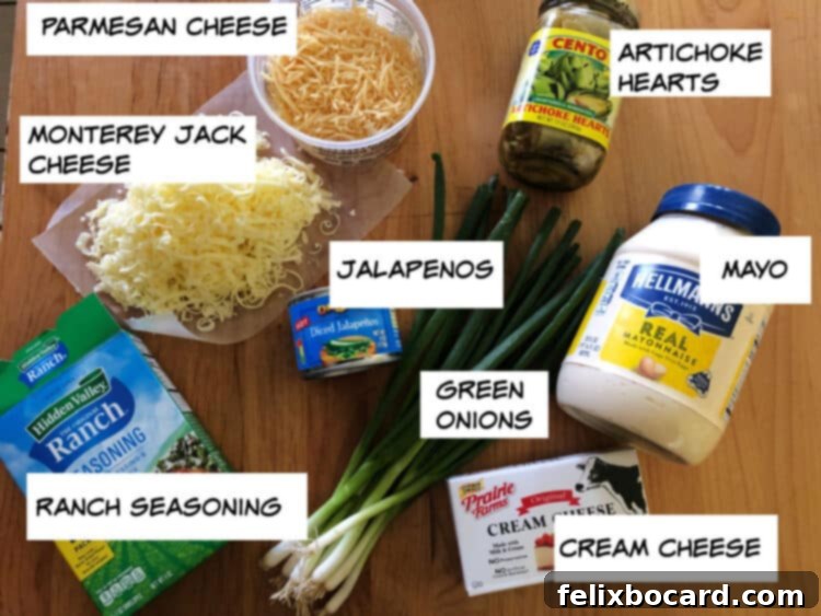 Bold Artichoke Jalapeno Dip 3 A visual display of all the ingredients needed for the jalapeno artichoke dip: parmesan cheese, monterey jack cheese, cream cheese, artichoke hearts, mayo, canned jalapenos, green onions, and ranch seasoning, neatly arranged on a white surface.
