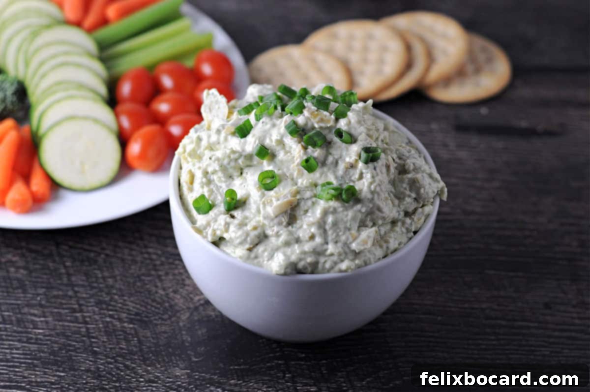 Bold Artichoke Jalapeno Dip 6 A beautifully presented bowl of creamy jalapeno artichoke dip, surrounded by an array of fresh vegetables like cucumber and bell pepper slices, alongside various crackers, illustrating perfect serving suggestions for any event.
