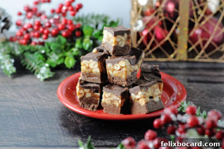 Stacked pieces of Snickers fudge on a small red plate, surrounded by festive holiday decorations, highlighting its appeal as a delicious holiday treat and easy dessert.