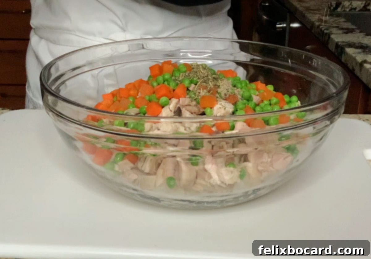 Mixing the ingredients in a bowl for turkey pot pie filling.