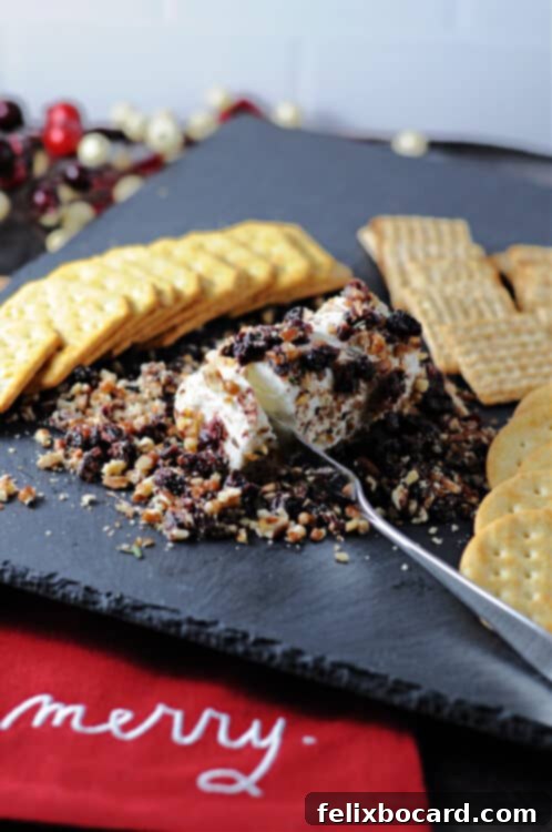 Festive cranberry goat cheese log on a slate cheese board with crackers for holiday entertaining