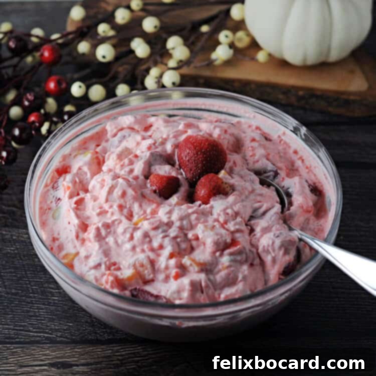 Close-up of strawberry tapioca fruit salad in a clear glass serving bowl, showcasing its creamy texture and vibrant fruit pieces.
