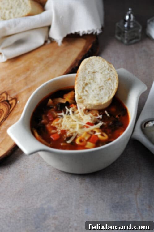 cup of instant pot minestrone soup garnished with shredded parmesan cheese and a slice of bread