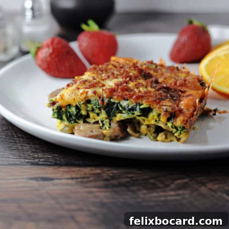 Keto Breakfast Casserole with Spinach, Bacon, and Eggs 2 Low Carb breakfast casserole on a white plate with fruit