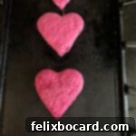 Heart shaped dragon fruit pancakes cooking on a griddle, showcasing their vibrant pink color