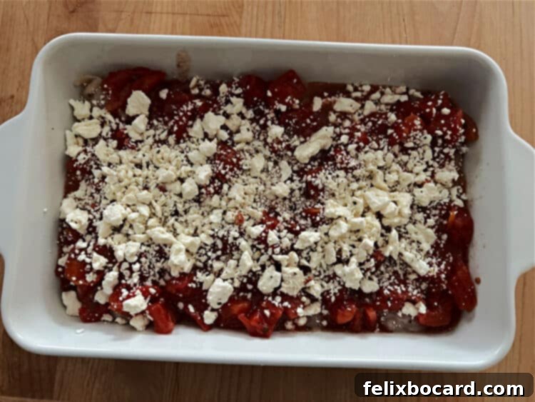 Mediterranean Feta Chicken Tenders 6 A baking dish filled with chicken and tomato mixture, topped with crumbled feta cheese, ready to be covered and baked.