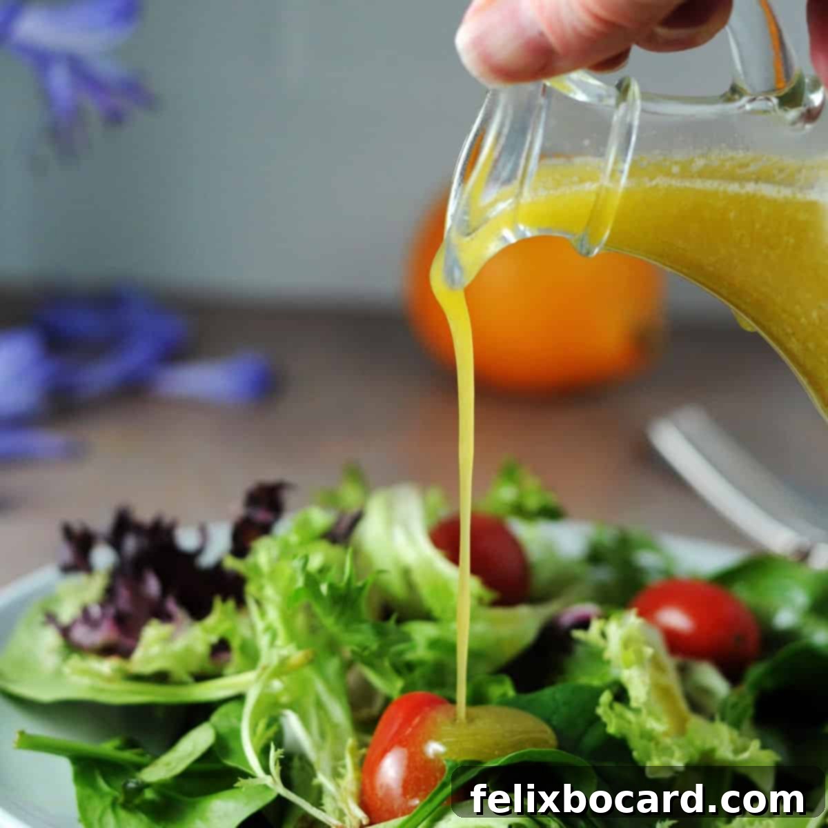 meyer lemon vinaigrette salad dressing pouring onto a salad