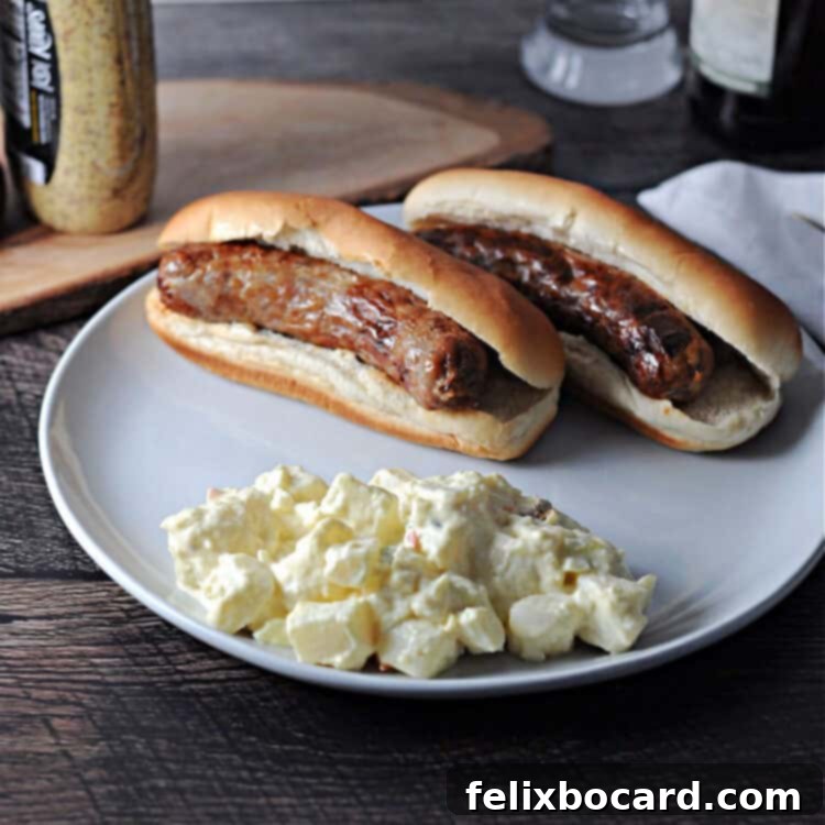 Two cooked brats nestled in buns on a plate, accompanied by a scoop of potato salad.