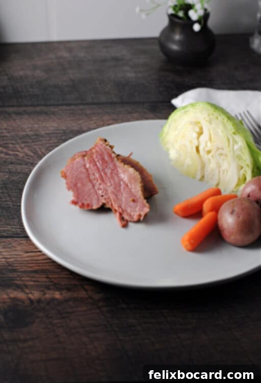 sliced corned beef on a plate with cabbage carrots and potatoes.