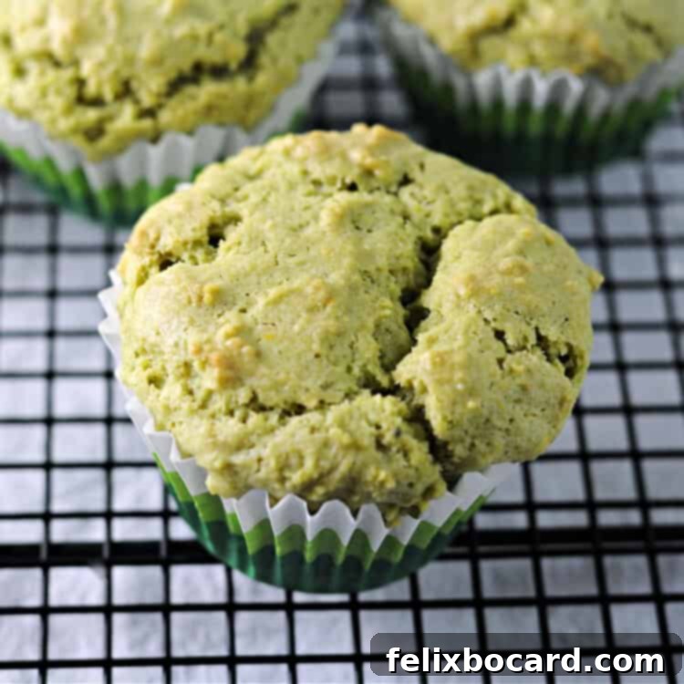 Freshly baked matcha green tea muffin cooling on a wire rack, showcasing its vibrant green color and light texture.