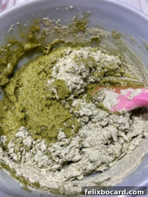 Wet and dry muffin batter ingredients being gently mixed with a spatula until just combined, ensuring a tender muffin texture.