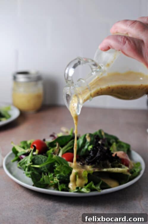 Red wine shallot vinaigrette pouring onto a fresh green salad, highlighting the vibrant color and appealing texture of the homemade dressing.