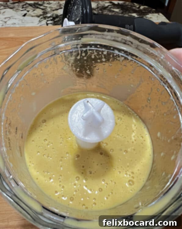 Top-down view of the vibrant red wine shallot vinaigrette actively blending in a small clear container, showcasing the beautiful emulsion forming.