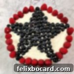 top view of decorated patriotic torte with large star made of blueberries surrounded by a circle of raspberries
