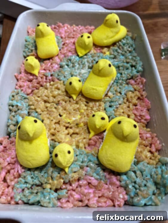 pan of peeps rice krispie treats decorated with whole peeps and some extra heads of peeps.