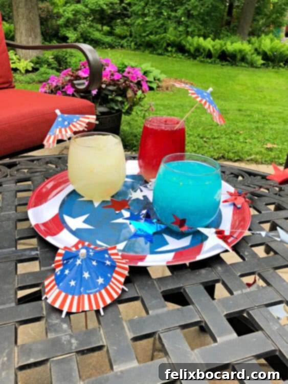 Patriotic Spirit Slush 2 Three layered red, white, and blue vodka slushes in tall glasses on a patriotic outdoor tray, perfect for a 4th of July celebration.
