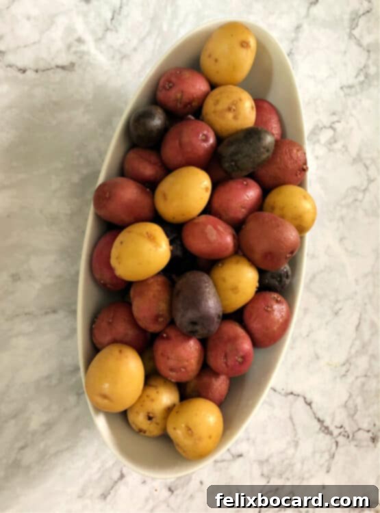 Raw tri-color potato medley in a white oval bowl, ready for cooking.
