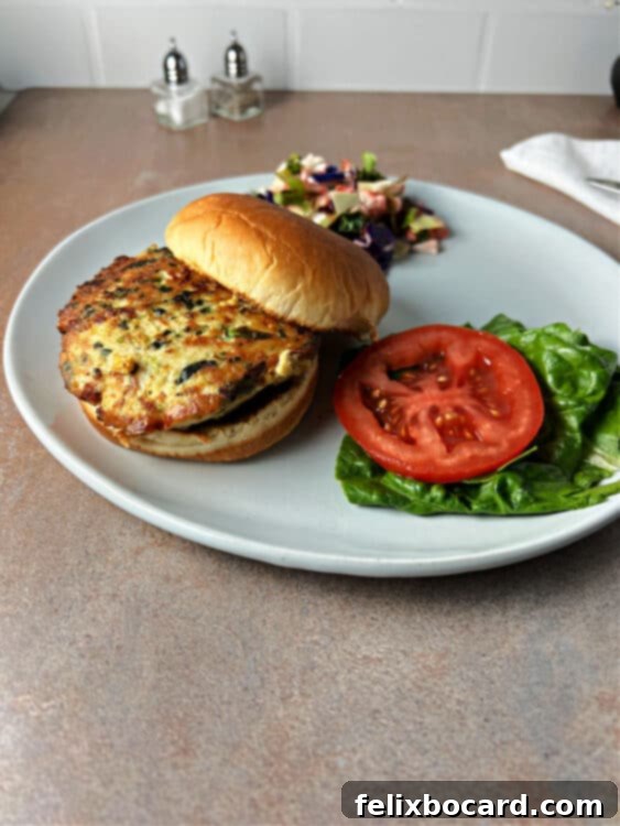 A perfectly cooked chicken feta spinach burger, featuring a juicy patty topped with vibrant green spinach and melted feta, nestled in a toasted bun, served on a rustic plate, ready to be enjoyed.